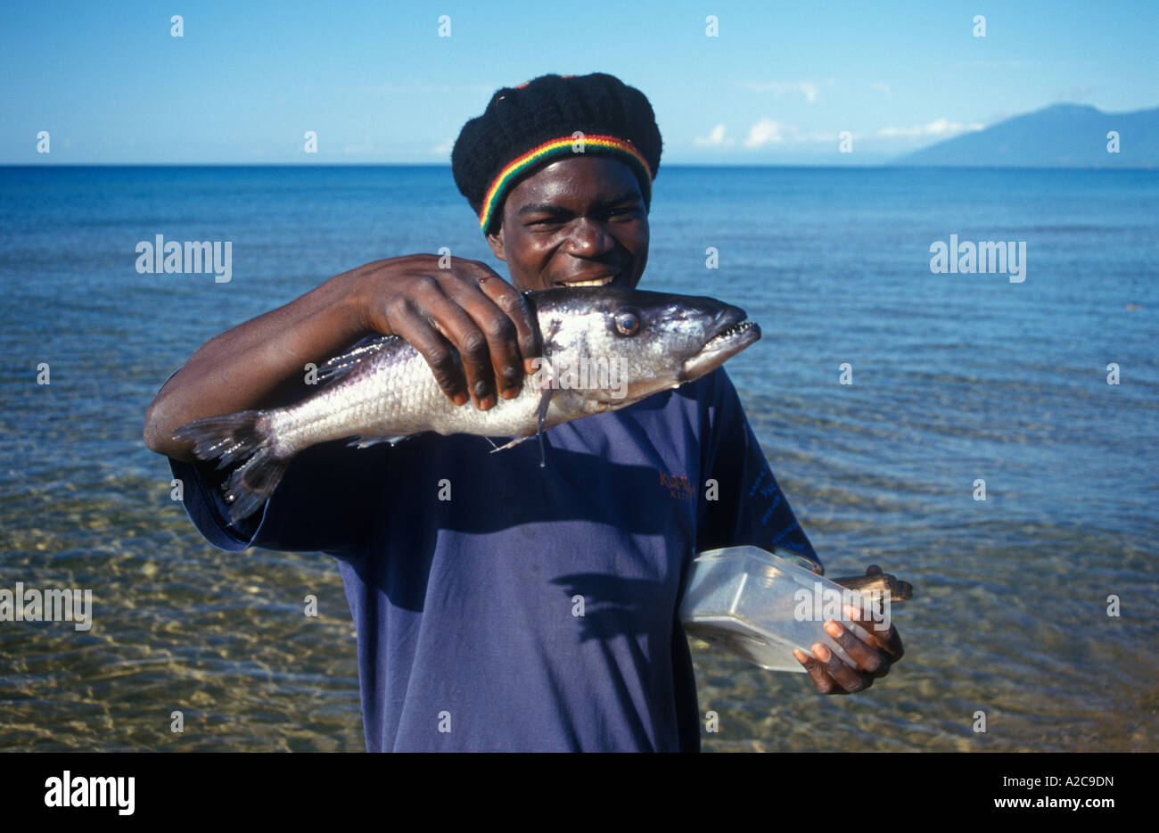 Nativo di una giovane uomo è la presentazione di un grande pesce che ha appena pescato nel Lago Malawi Foto Stock
