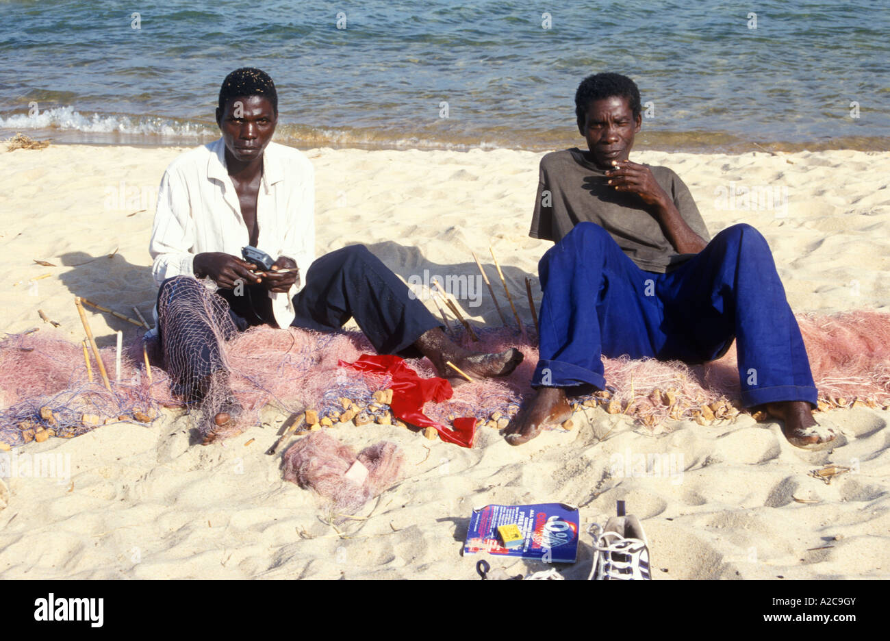 I pescatori riassettavano le reti a Kande Spiaggia al lago Malawi in Africa Foto Stock