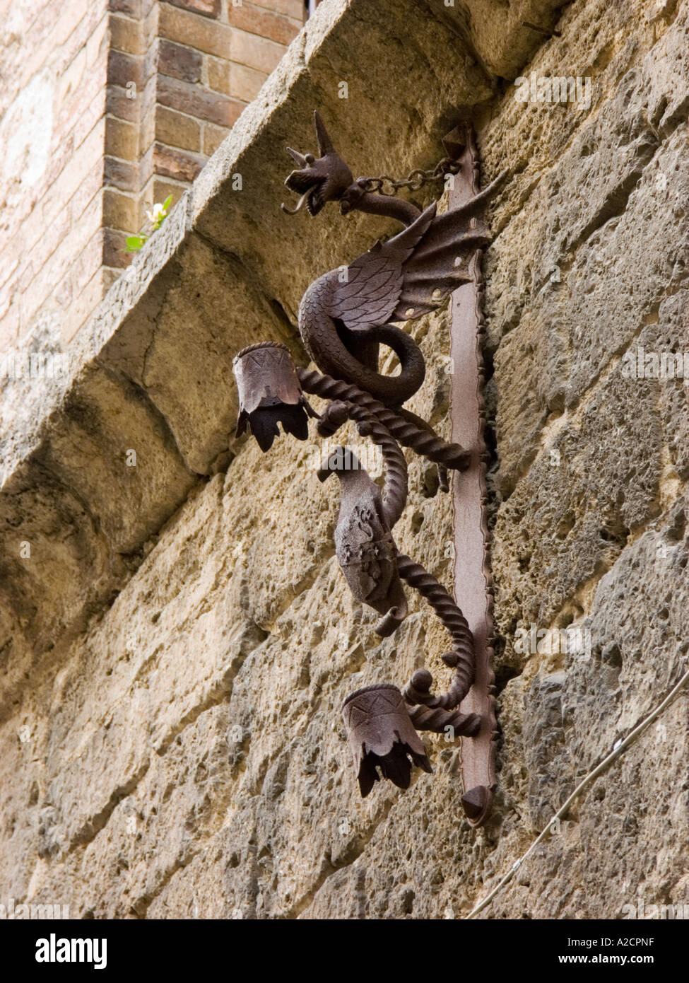 Ferro decorativo di lavoro su un muro di pietra in Sangimignano Italia Foto Stock