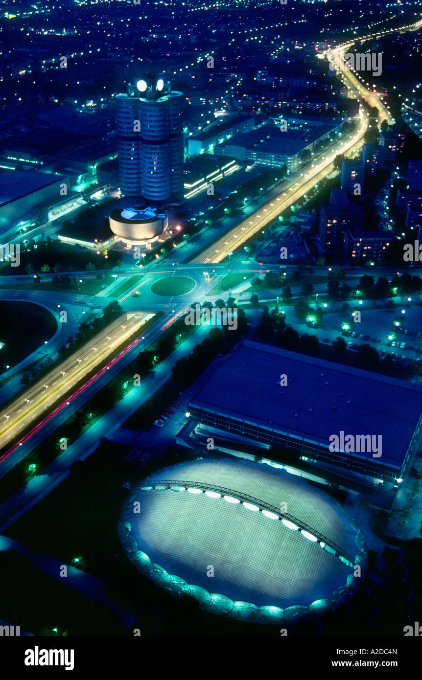 Birds Eye vista illuminata dell'edificio della BMW e il Villaggio Olimpico e le strade di Monaco di notte, Germania Foto Stock