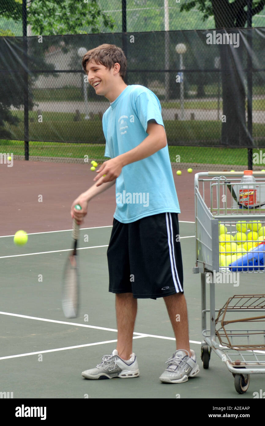 Teenage Tennis maschile tutor dando lezioni in un pubblico di estate programma scolastico Foto Stock