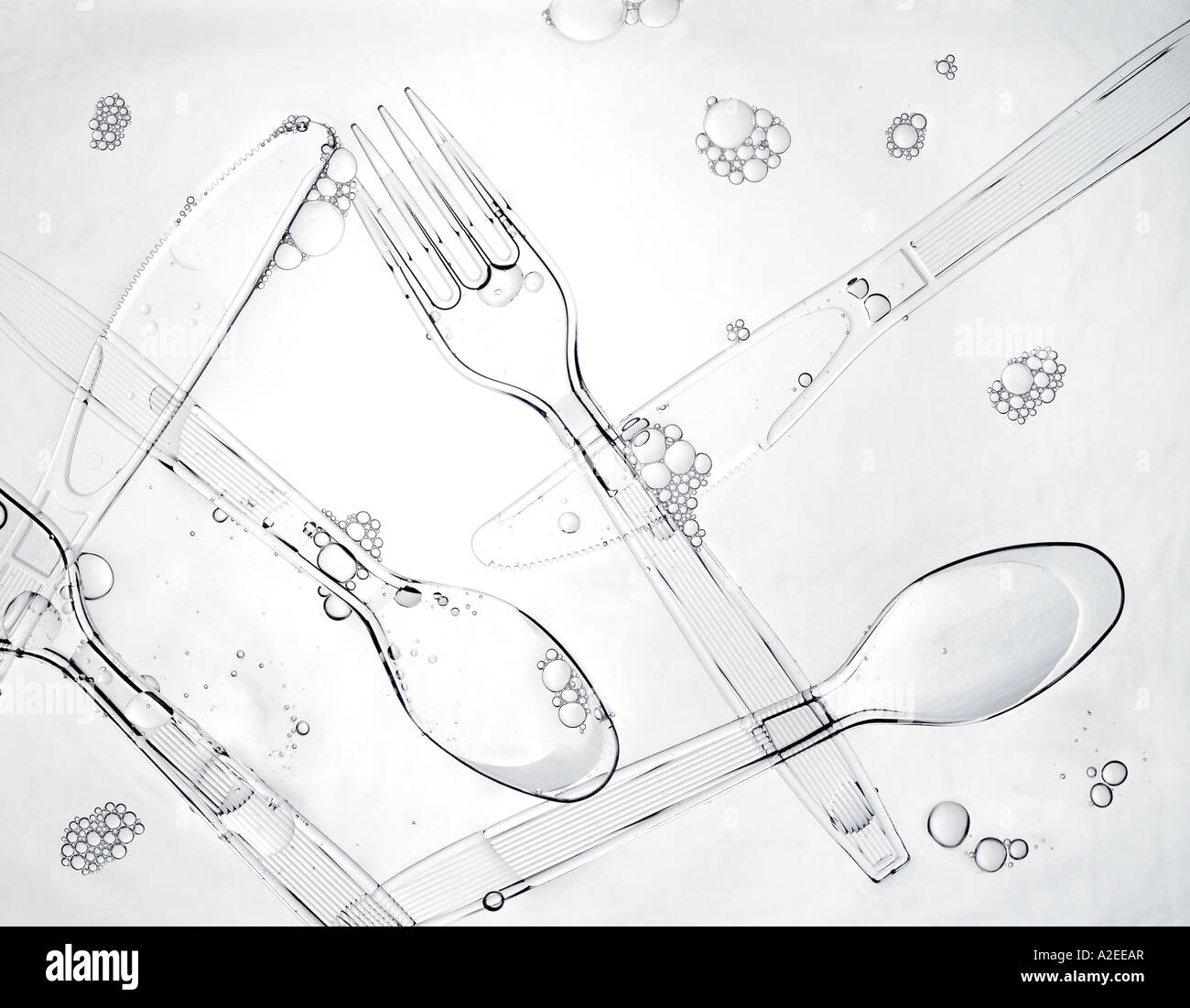Chiara forcella di plastica, il coltello e il cucchiaio nella saponata acqua di lavaggio con bolle Foto Stock