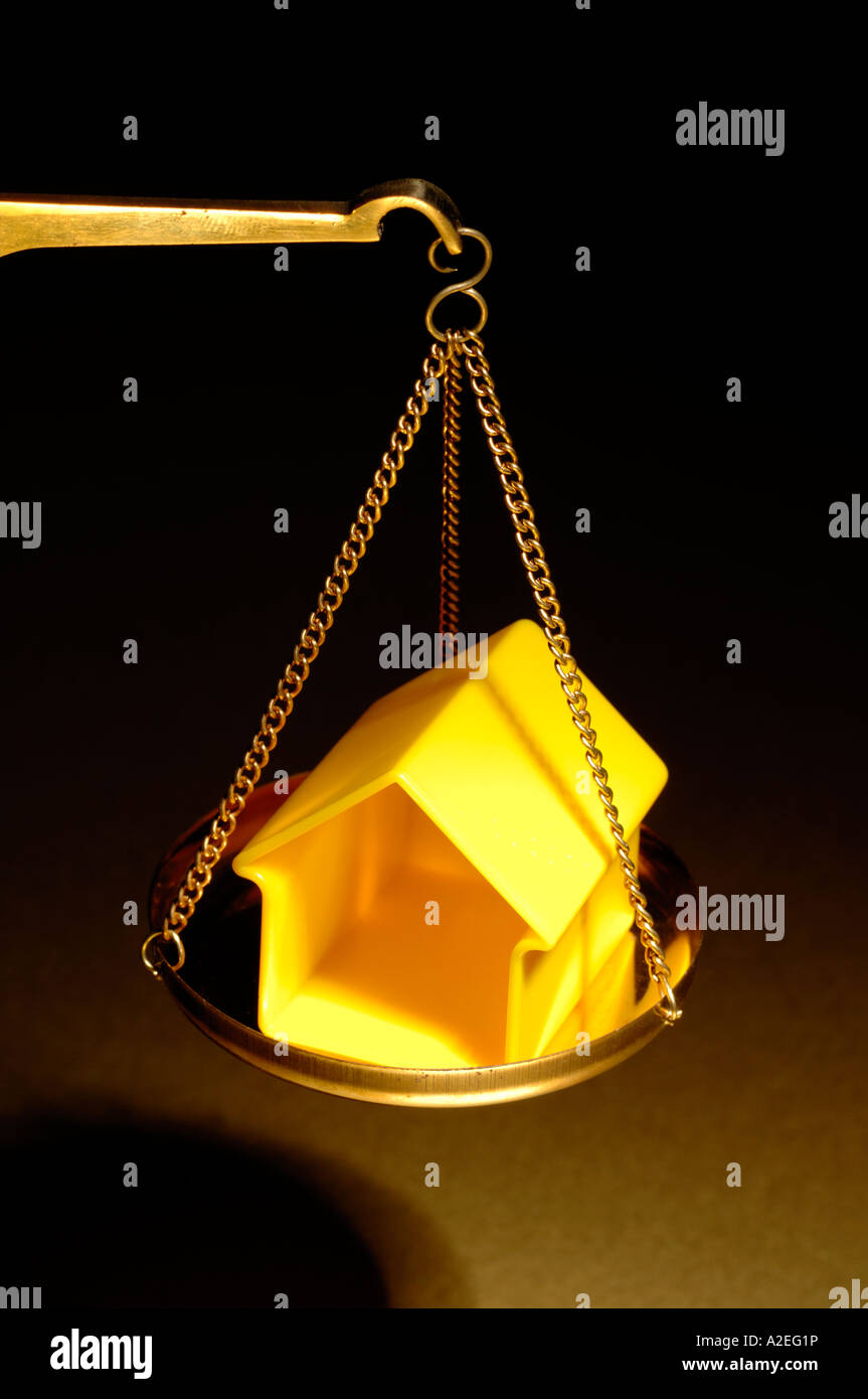 In plastica gialla forma casa su una scala in ottone Foto Stock
