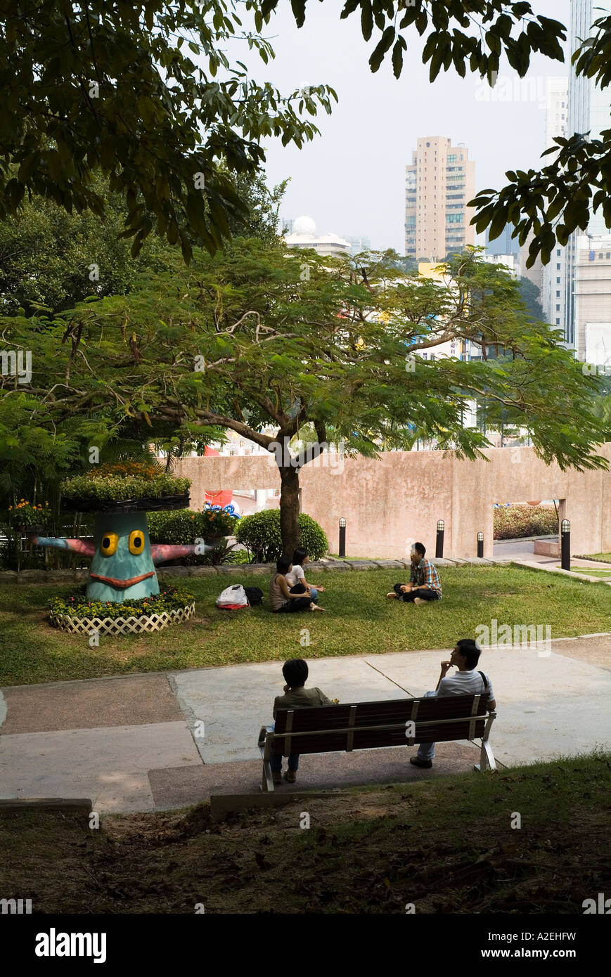 dh Kowloon Park TSIM SHA TSUI HONG KONG gente rilassante su erba e panchine in panca del parco sedersi giardino Foto Stock