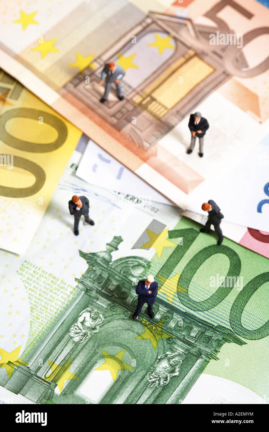 Statuette in piedi sulle banconote in euro Foto Stock