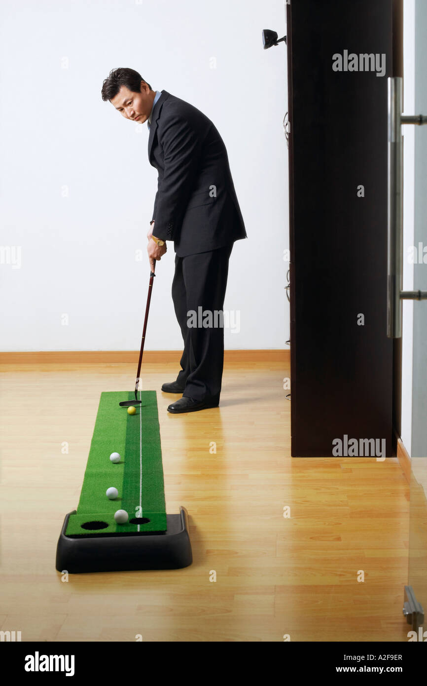 Il profilo laterale di un imprenditore la pratica del golf in un club Foto Stock