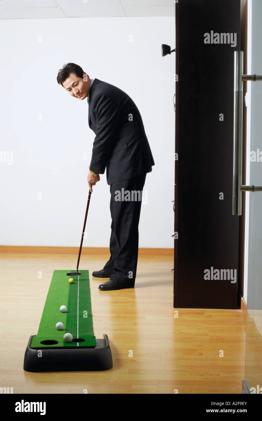 Il profilo laterale di un imprenditore la pratica del golf in una stanza Foto Stock