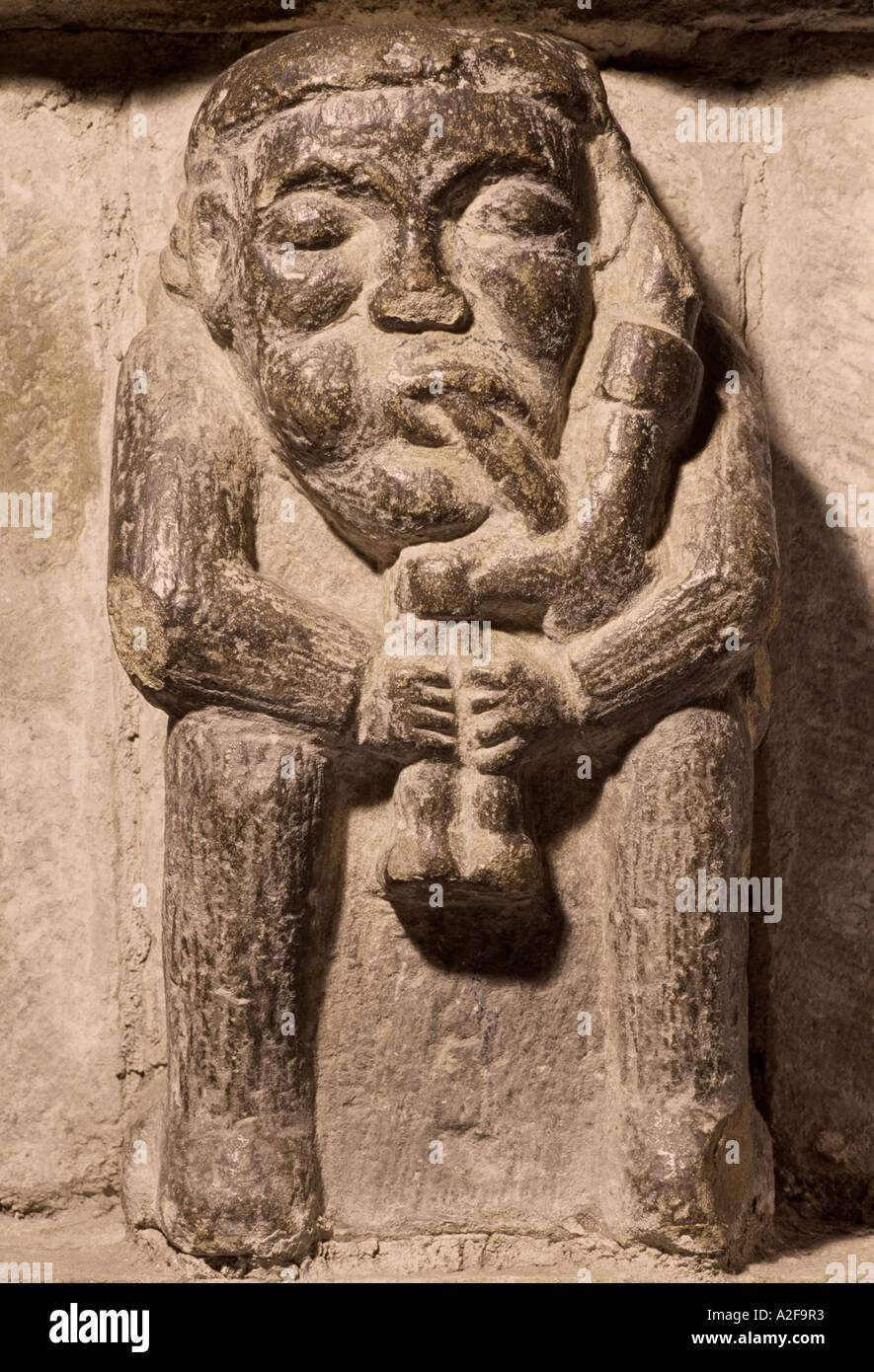 Hexham Abbey, Northumberland, 1170 - 1250. Inizio di stile Inglese. Scultura in pietra di un uomo giocando Northumbrian pipe. Foto Stock