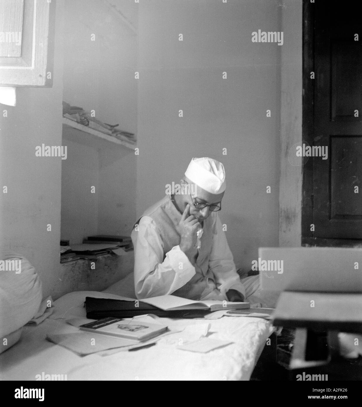 Jawaharlal Nehru nel cappuccio giacca seduta a pensare la lettura sul materasso a Bhangi Spazzatrici Colony New Delhi India 2 Ottobre 1946 Foto Stock