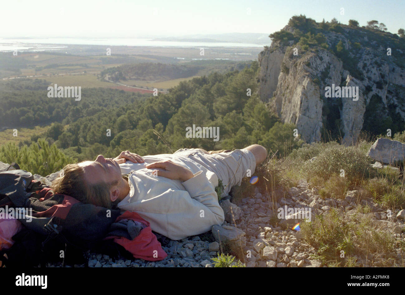 Uomo appoggiato sulla cima di una collina con vista sul lago Foto Stock