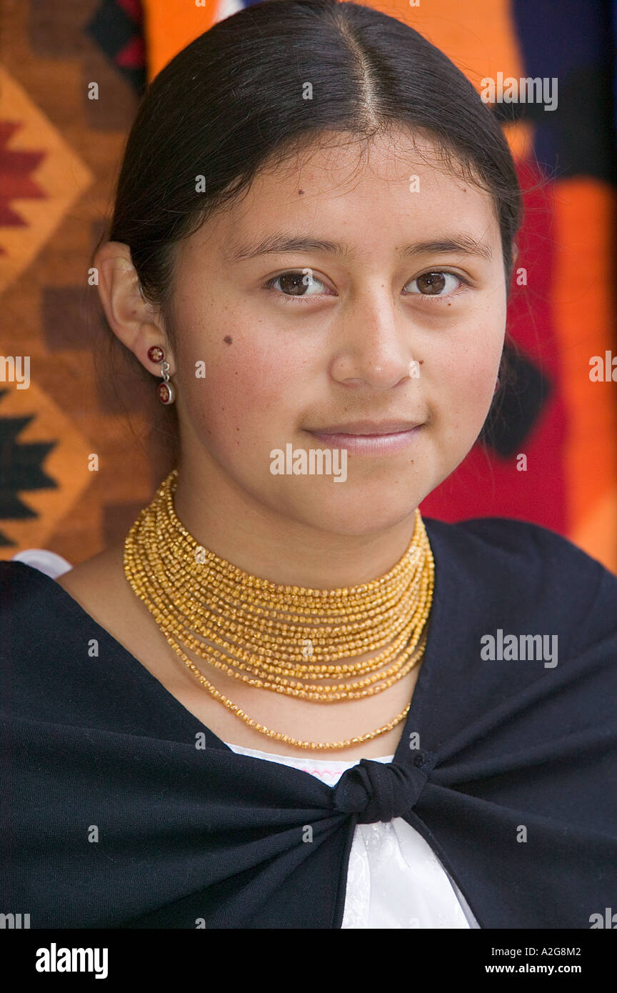 Giovani, tradizionalmente vestiti donna ecuadoriana si siede di fronte a mano tappeti tessuti Foto Stock