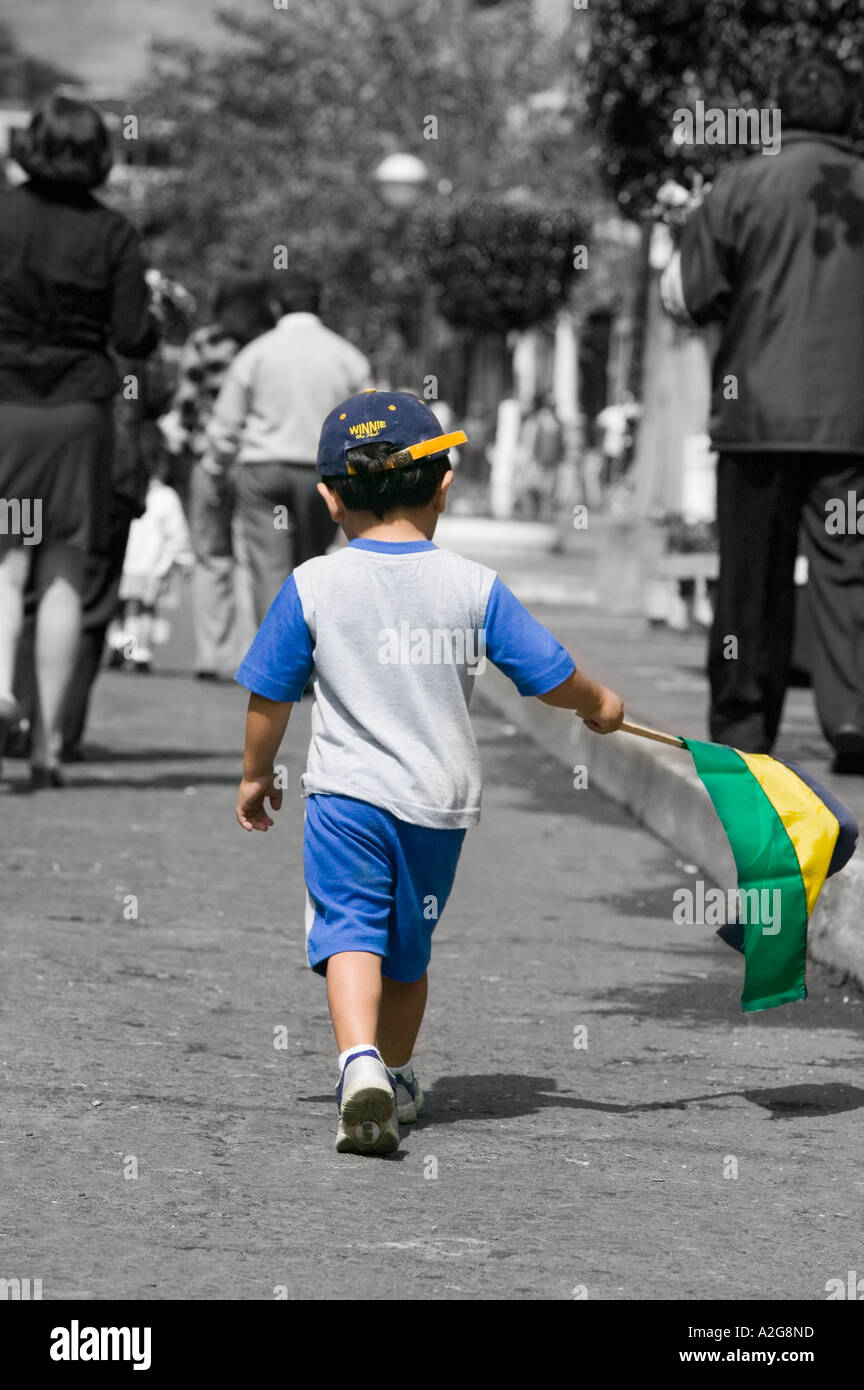 Ragazzo giovane cammina con bandiera durante la celebrazione annuale in Banos, Ecuador Foto Stock