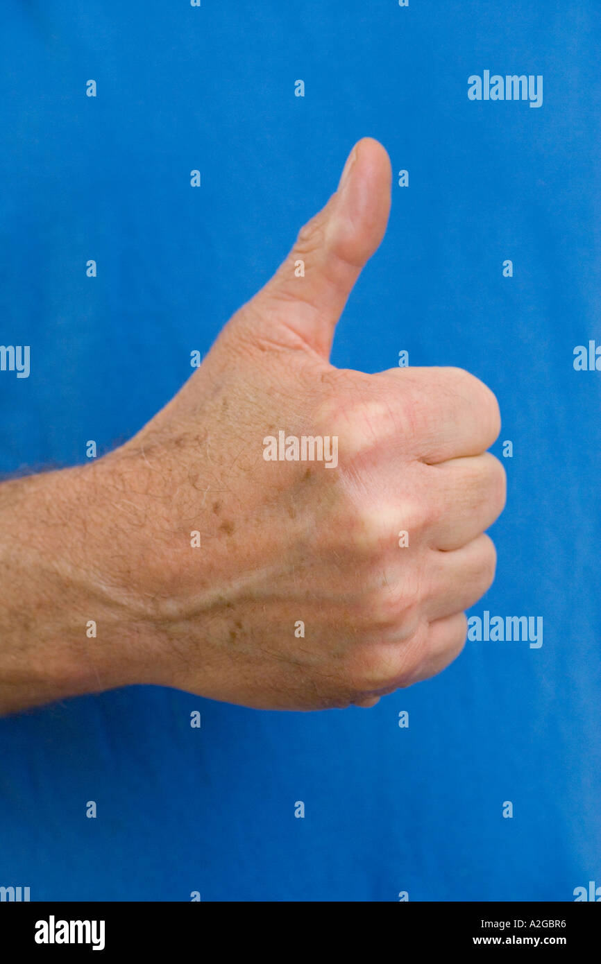 L uomo dà pollice in alto segno contro sfondo blu Foto Stock
