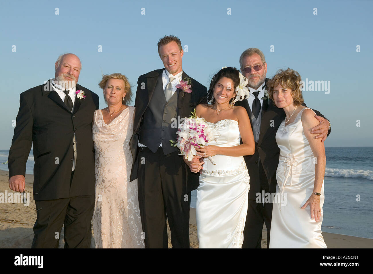 Ritratto di sposa e lo sposo con entrambi i gruppi di genitori al matrimonio sulla spiaggia a Malibu, California Foto Stock