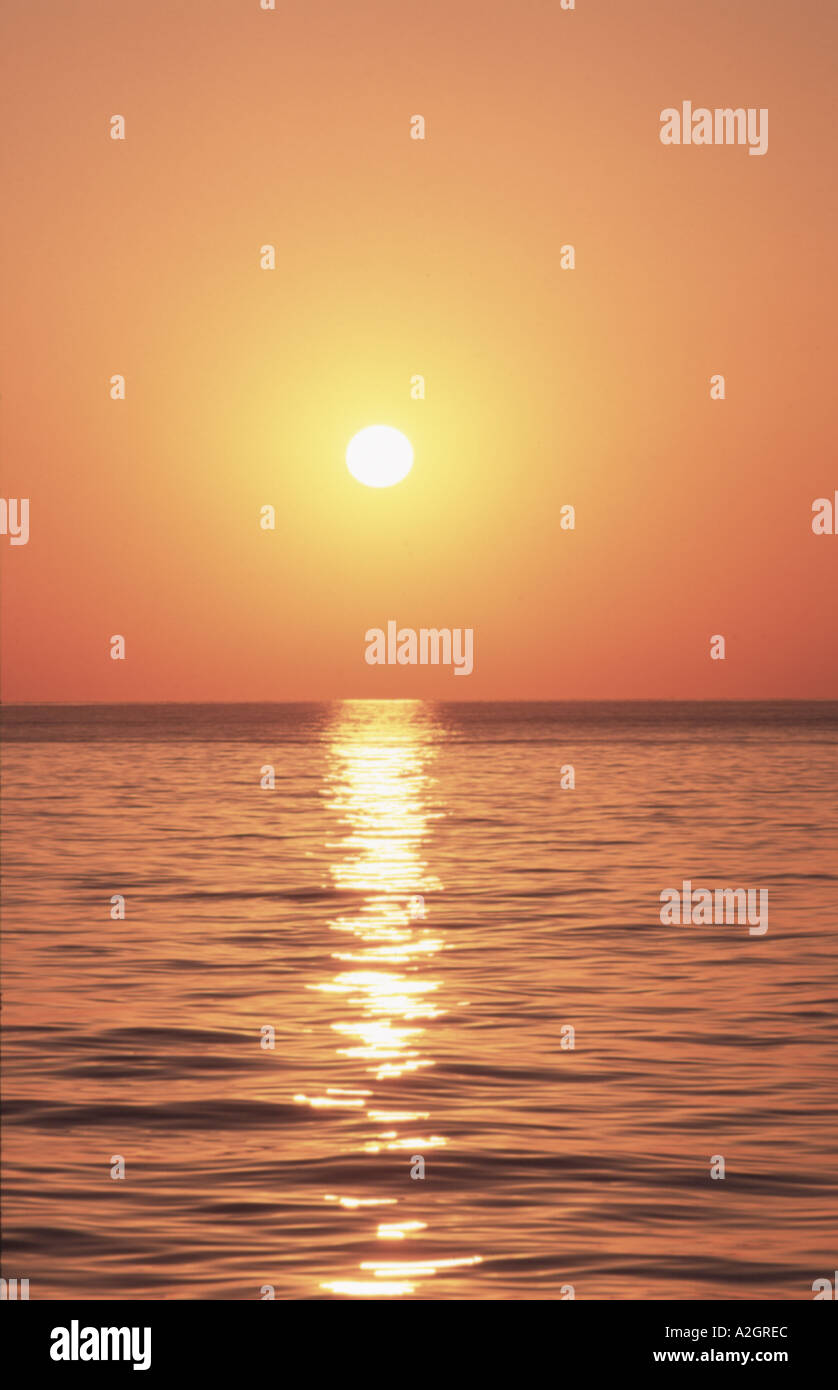 Tramonto del Mediterraneo con il sole di setting riflettente delicatamente in acqua increspata Foto Stock