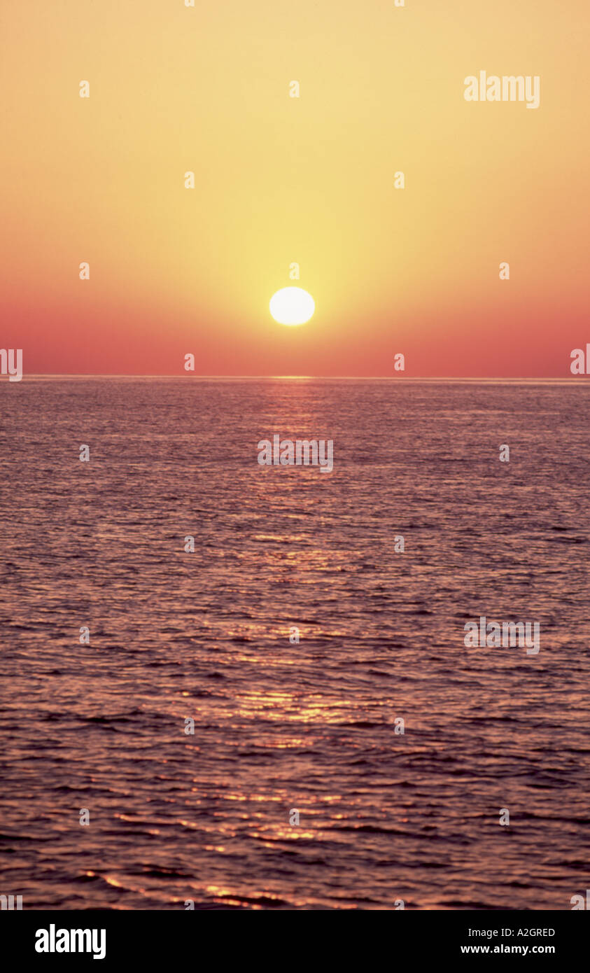 Tramonto del Mediterraneo con il sole di setting riflettente delicatamente in acqua increspata Foto Stock