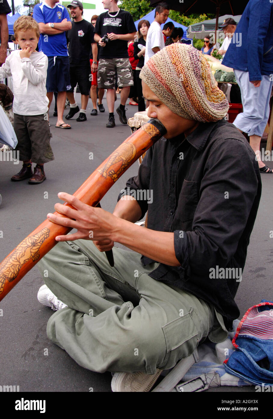 Street busker giocando scolpiti aborigeno didgeridoo, Takapuna domenica street market, North Shore di Auckland Nuova Zelanda Gennaio 2007 Foto Stock