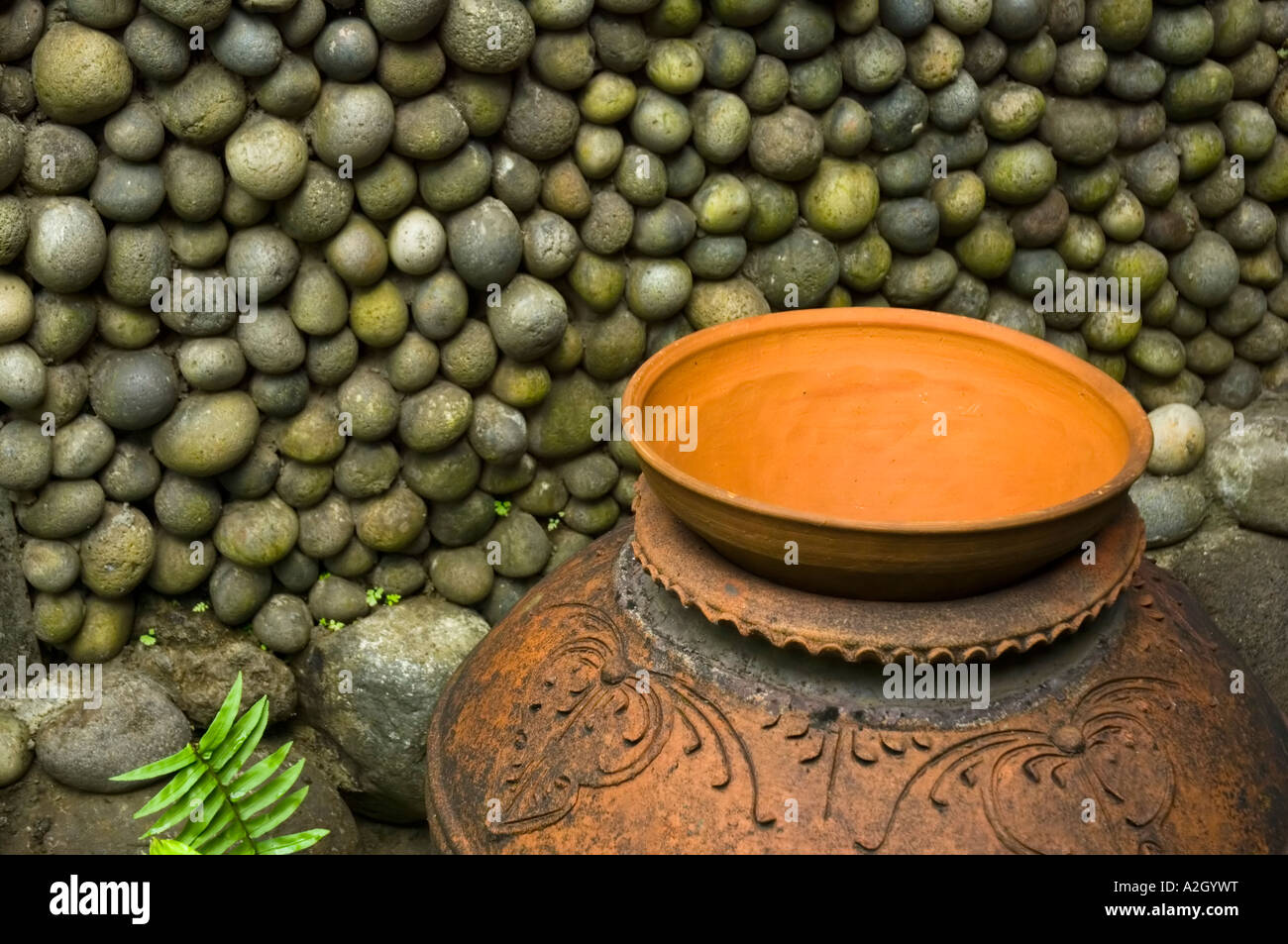 Indonesia Bali Ubud Ladybamboo Villa pentola di creta nella parte anteriore della parete formata da ciottoli Foto Stock