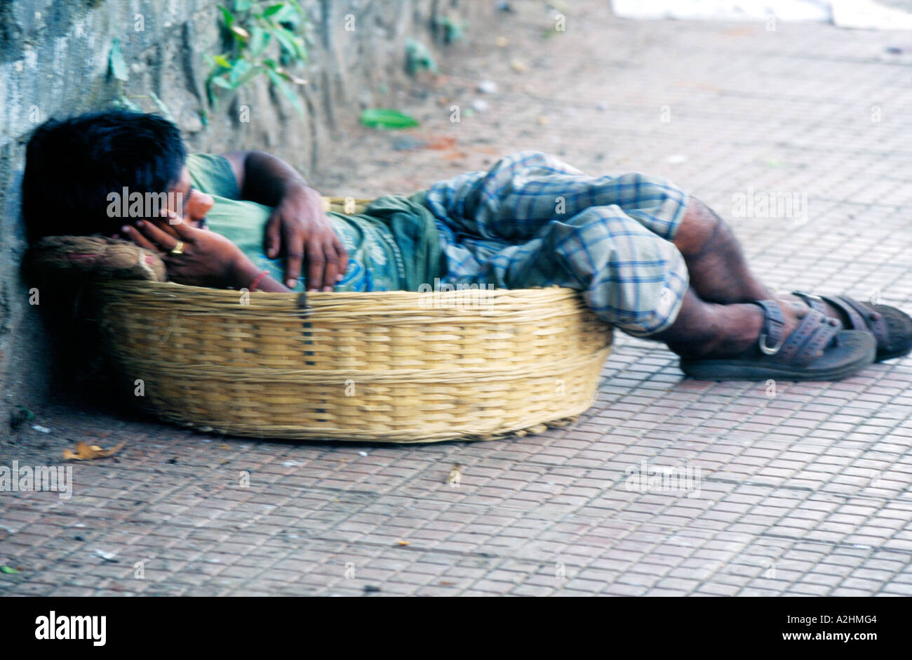 Un portiere (coolie) assume un ben meritato la funzione snooze a mezzogiorno nel suo cesto di vimini (tokra) a Mumbai della Crawford Mercato, India. Foto Stock