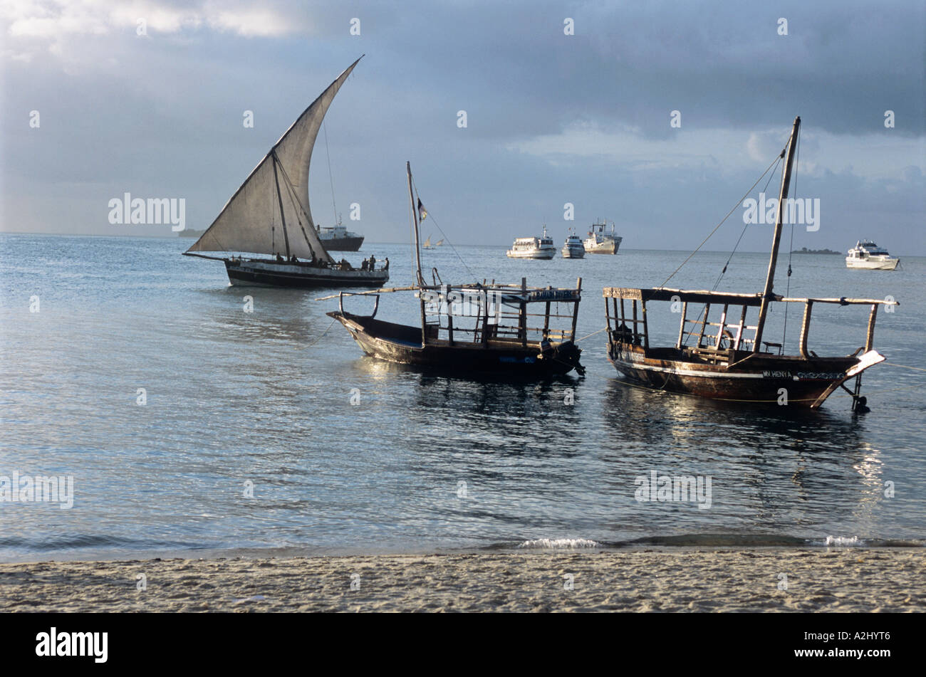 Un piccolo dhow a vela e altre imbarcazioni a riposo nella luce della sera a Zanzibar del piccolo porto Foto Stock
