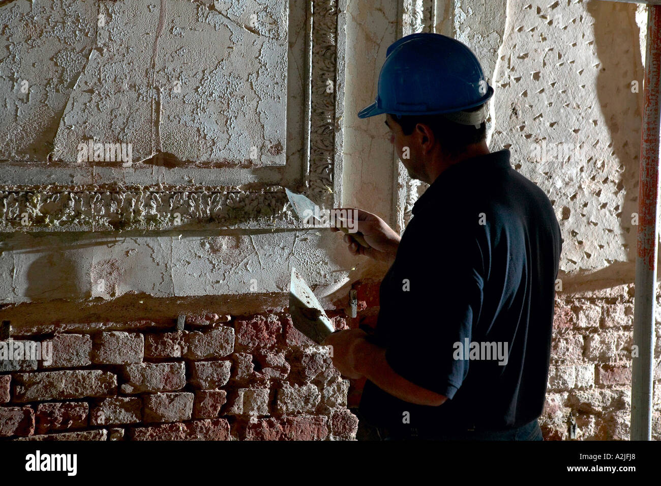 Un lavoratore a contratto smussa alcuni gesso sopra durante una fase di ristrutturazione della casa. Foto Stock