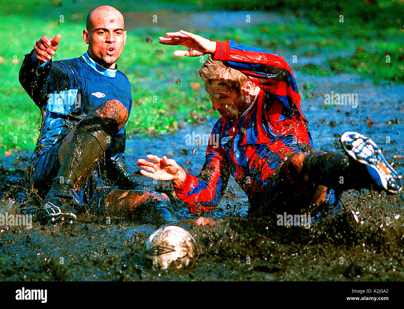 2 calciatori età 20-25 giocando a calcio su un campo fangoso. Foto Stock