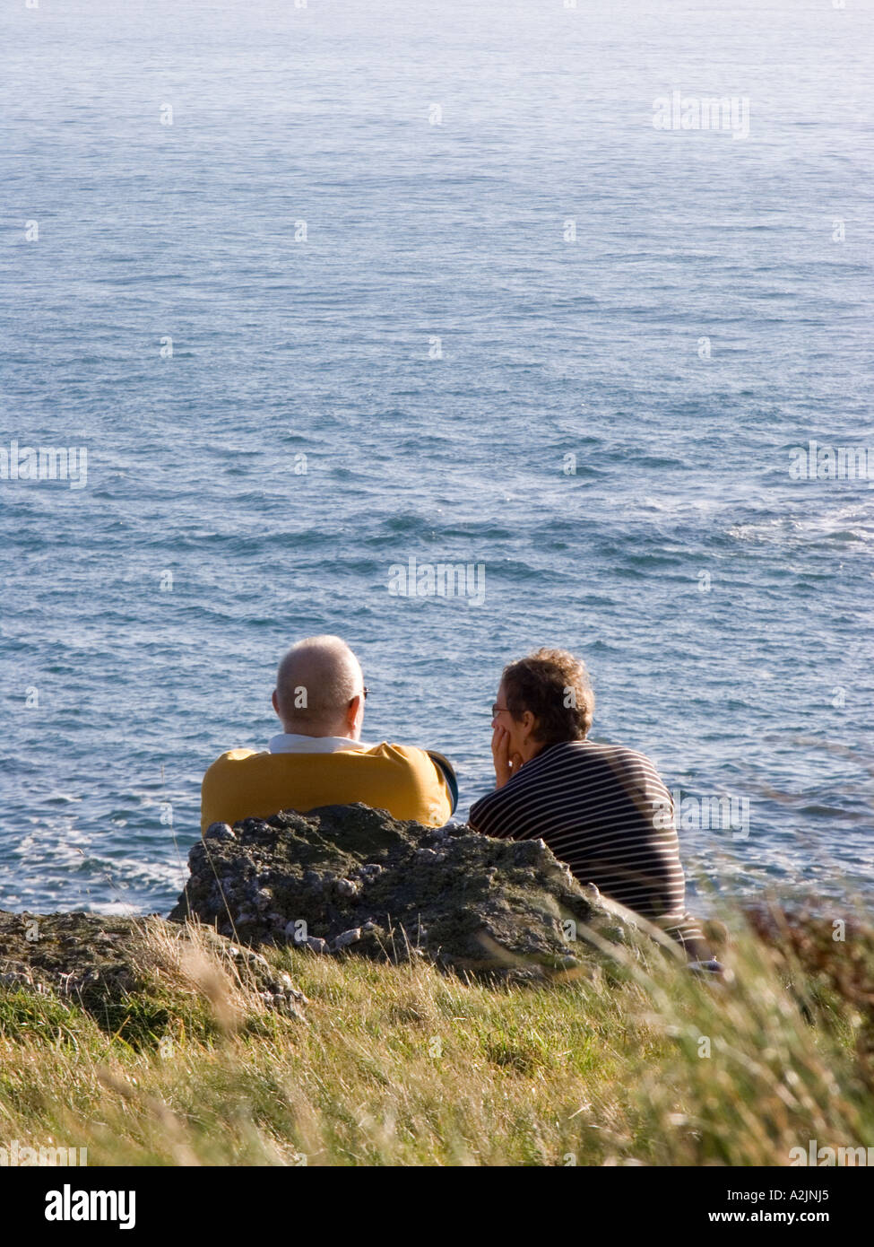 Di mezza età giovane godendosi un po' di sole invernale sulla costa al punto di partenza, Devon. Regno Unito Foto Stock