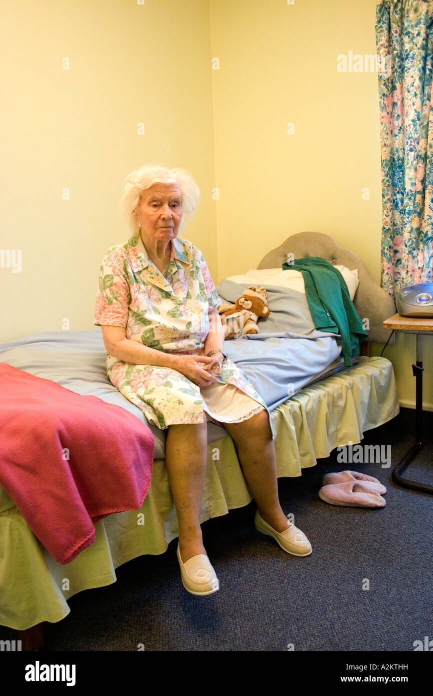 Infelice signora anziana in casa di riposo seduto sul bordo del letto Foto Stock