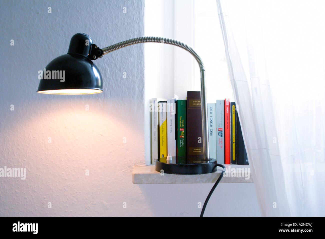 Libri e angolo-poise lampada sul davanzale Foto Stock