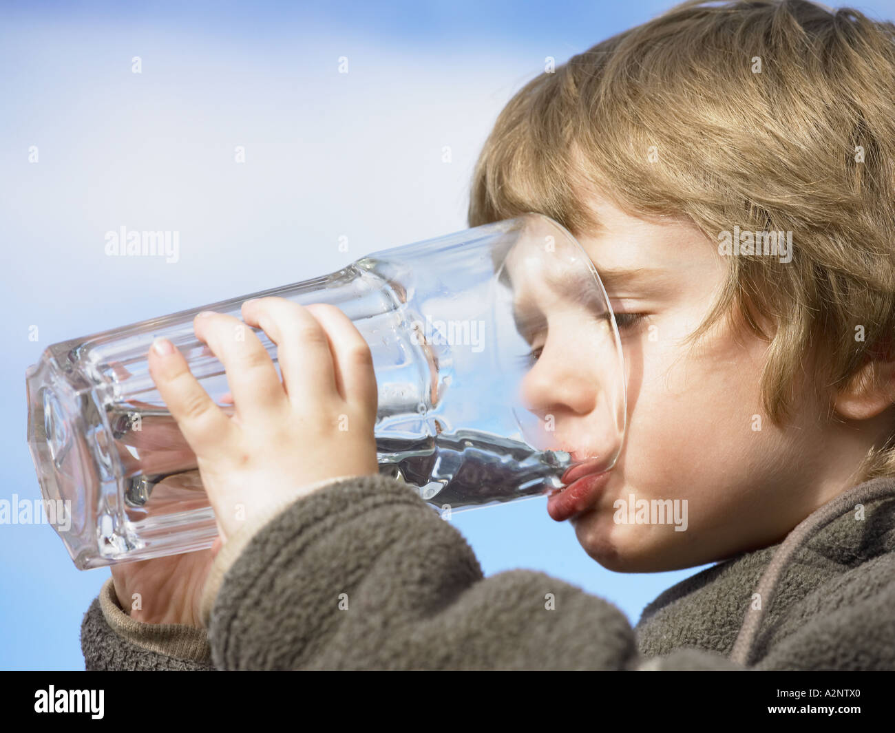 Un giovane bambino bere un bicchiere di acqua da una grande in stile  caffetteria bicchiere bicchiere esterno in una giornata di sole Foto stock  - Alamy
