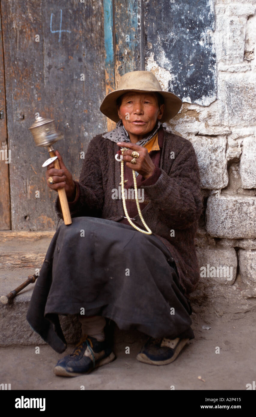 Donna anziana pellegrino con grani di preghiera e una ruota di preghiera, sul pellegrinaggio Barkhor circuito, Lhasa, in Tibet Foto Stock