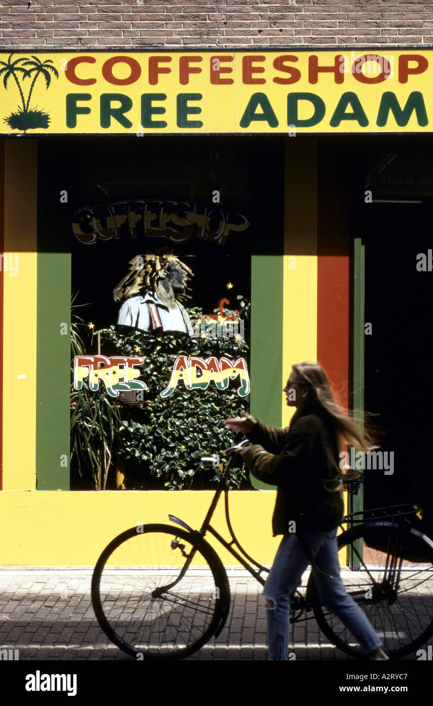 Giovane donna spingendo il suo passato di bicicletta un coffee shop in Amsterdam Foto Stock