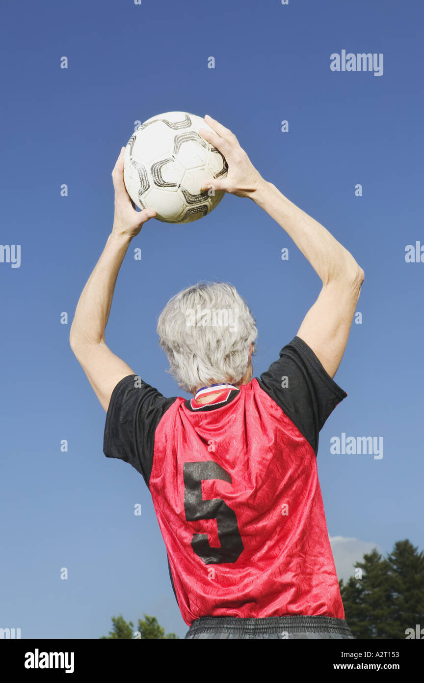 Una femmina matura giocatore di calcio lancia la palla in Foto Stock