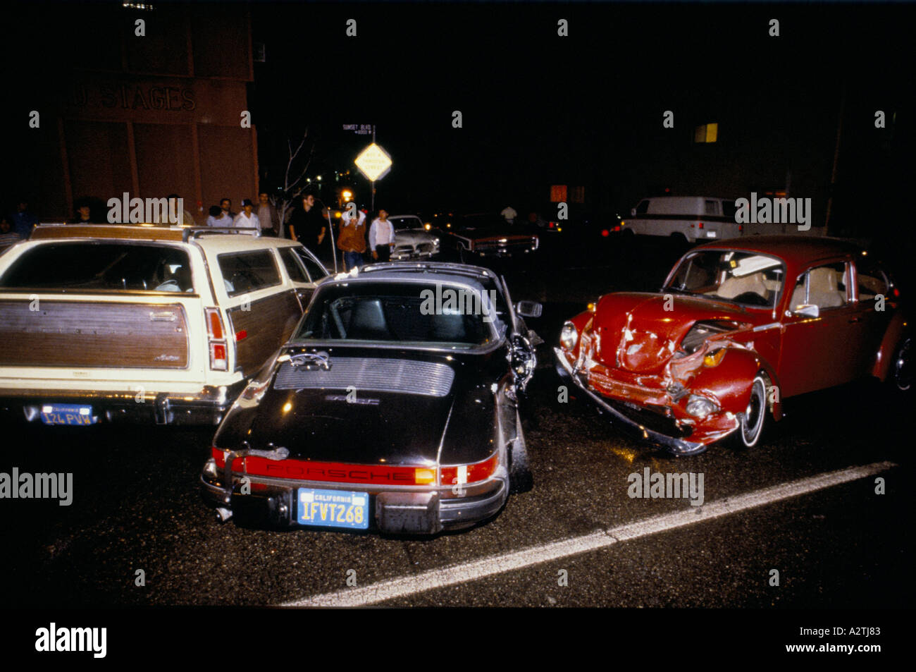 Tre vetture tra cui una Porsche con la California targhe e una station wagon sono coinvolti in una notte tempo crash di strada su una strada di città di Los Angeles che la gente guarda il relitto da tutta Foto Stock