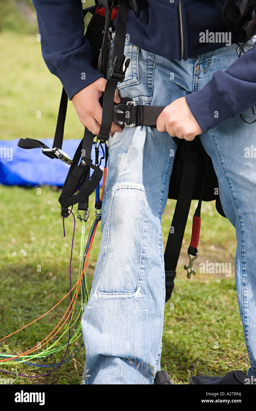 Parachutist maschio regolando il suo equipaggiamento Foto Stock