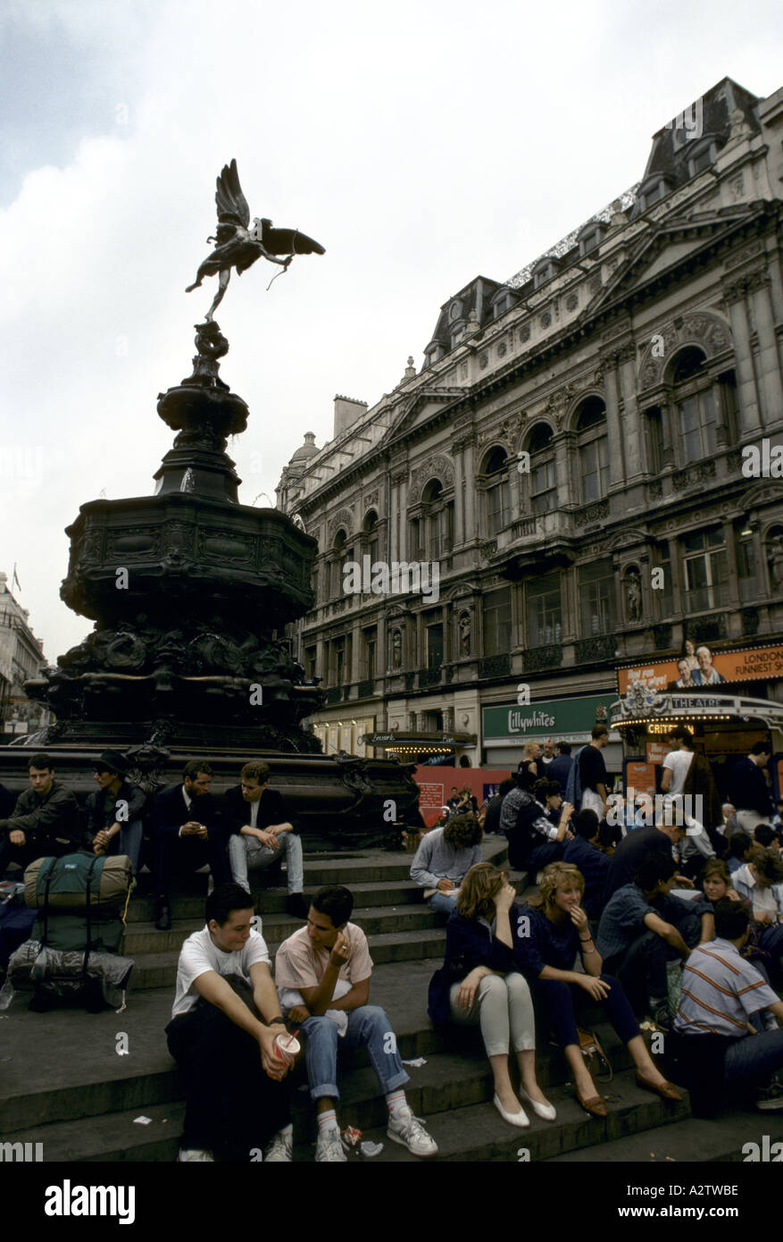 Turisti che si siedono sui gradini della statua di Eros, Piccadilly, Londra Foto Stock