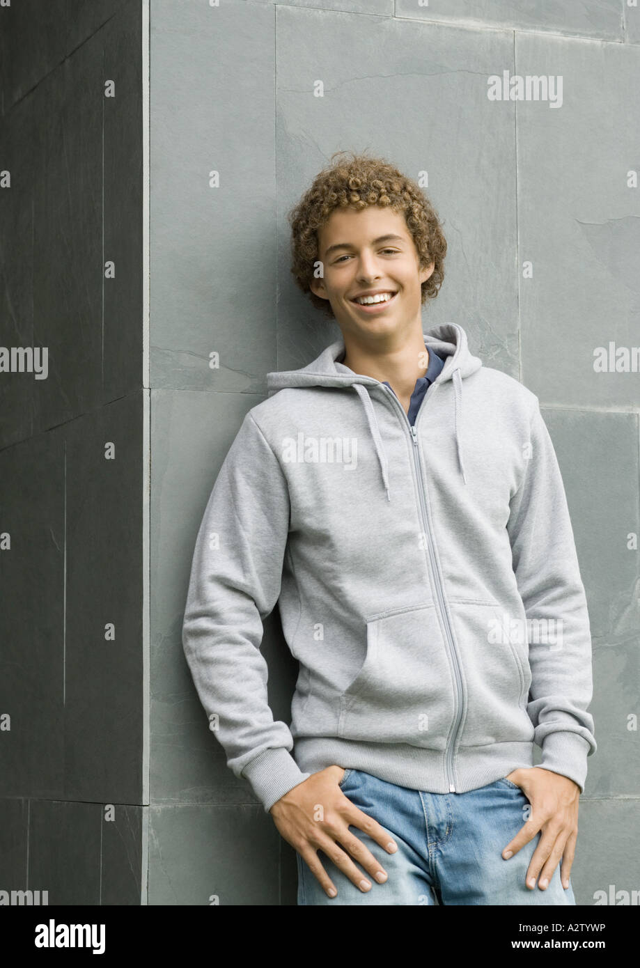 Giovane uomo in piedi con i pollici in tasche, sorridente in telecamera Foto Stock