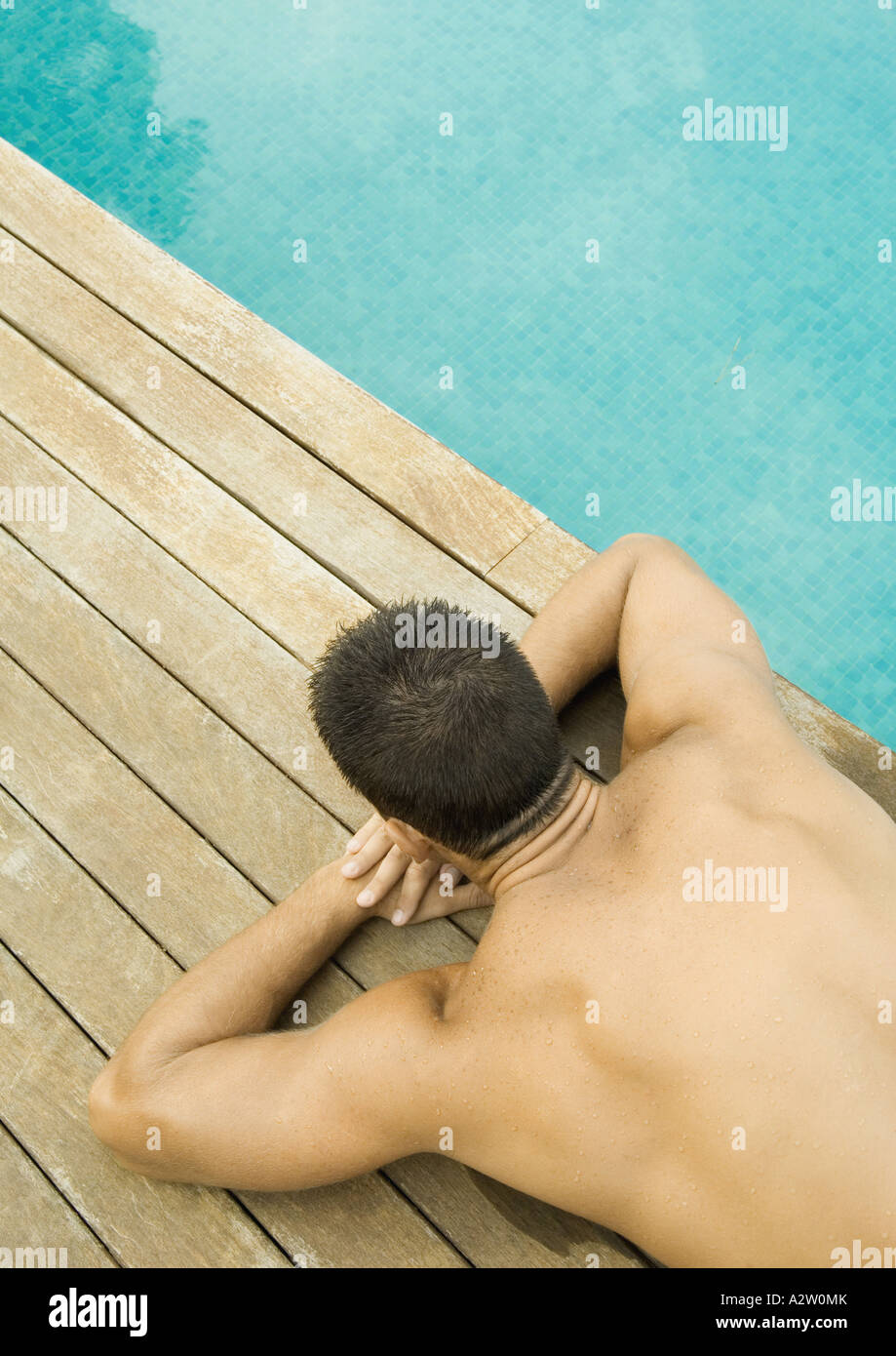 Uomo disteso dal bordo della piscina, alla cintura verso il basso Foto  stock - Alamy