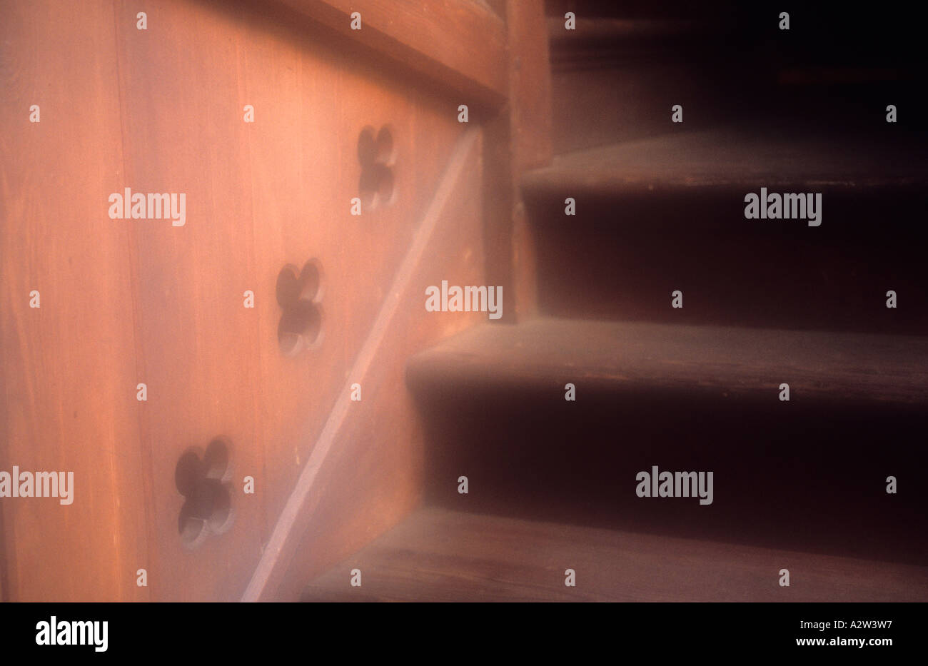 Dettaglio atmosferica di un giro in una scala di legno con un pannello su un lato con ritagli quatrefoil Foto Stock