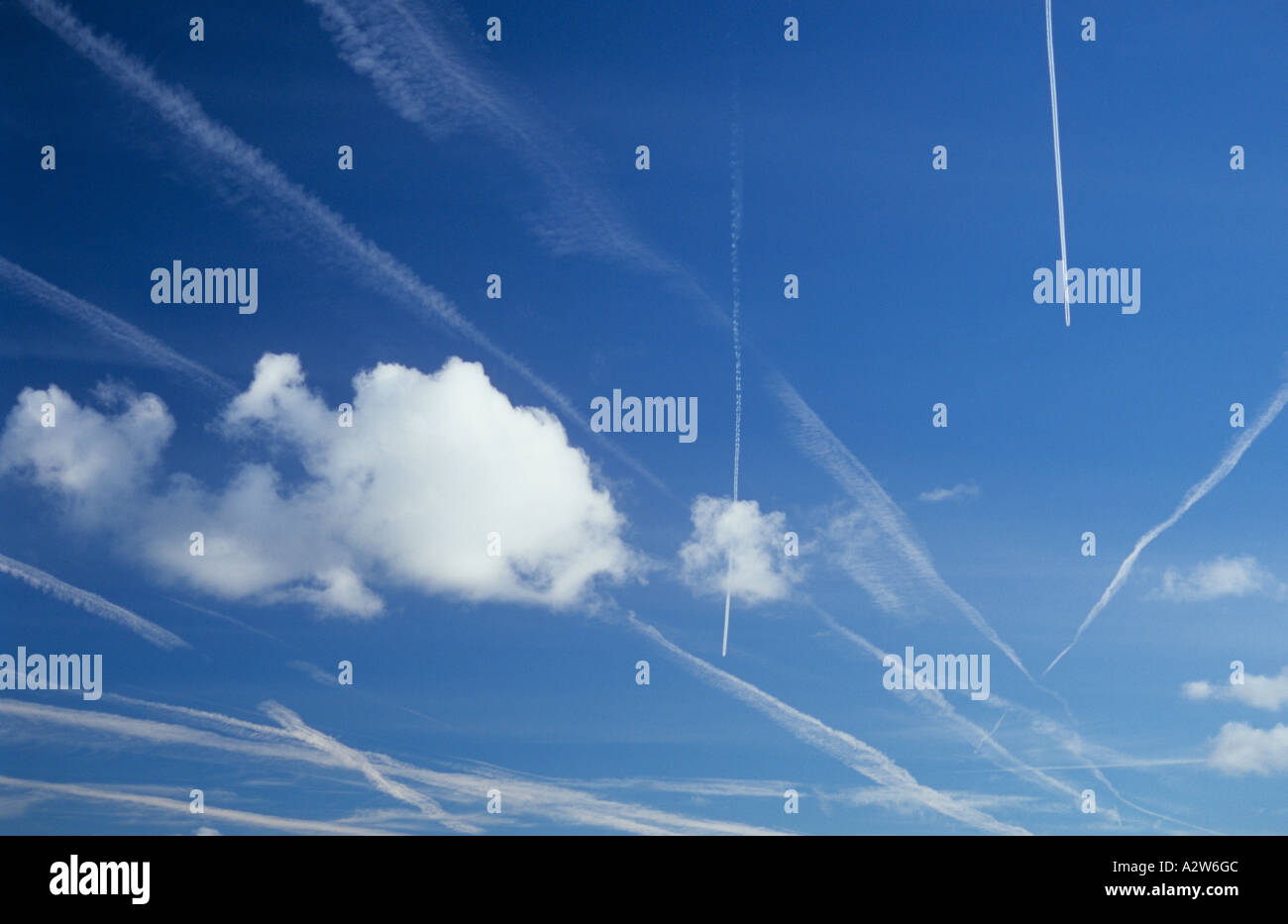 Blue sky affollato con vapore sentieri o contrails recenti e attuali e con piccoli cumuli di nuvole Foto Stock