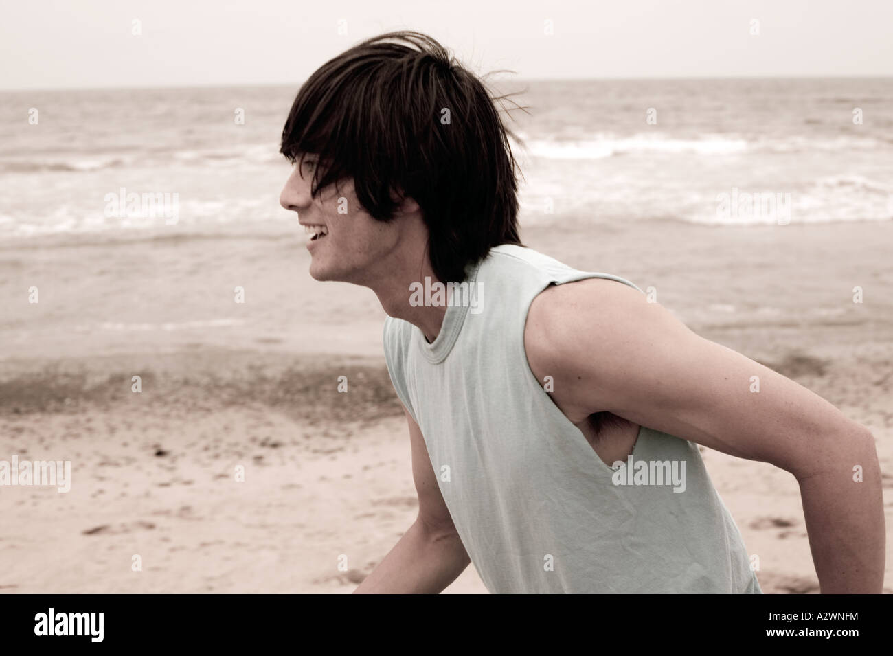 Giovane uomo che corre sulla spiaggia, sorridente Foto Stock