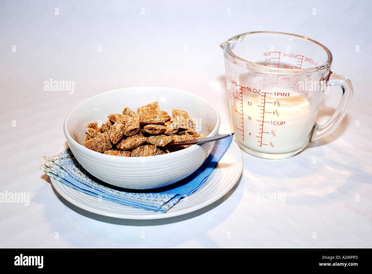 Shreaded frumento Cereali per la colazione in una ciotola bianca con una brocca del latte. Foto Stock