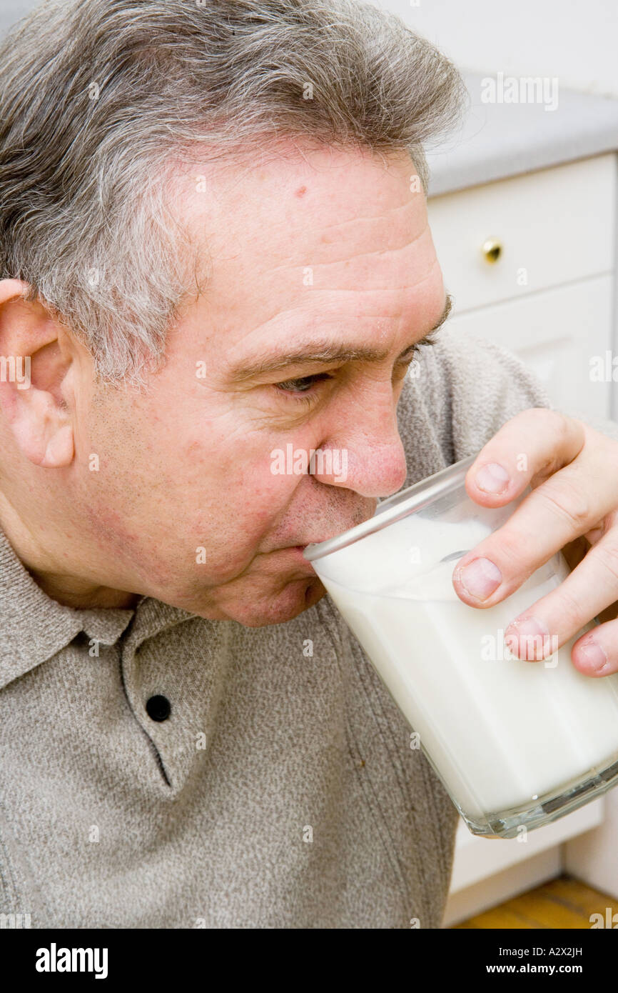 Maschio adulto gode di un bicchiere di latte. Foto Stock
