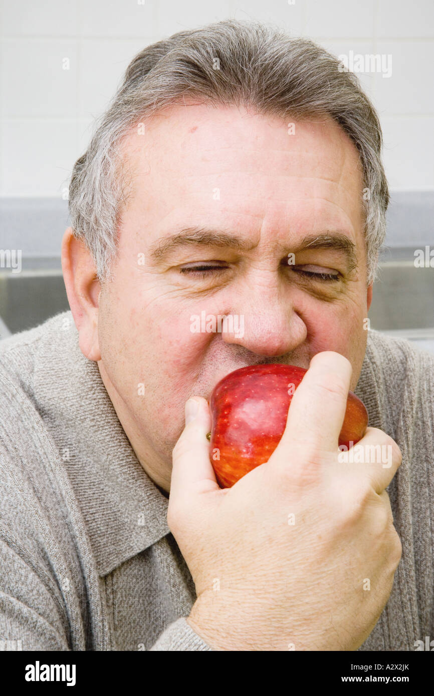 Senior uomo mangiare una mela rossa Foto Stock