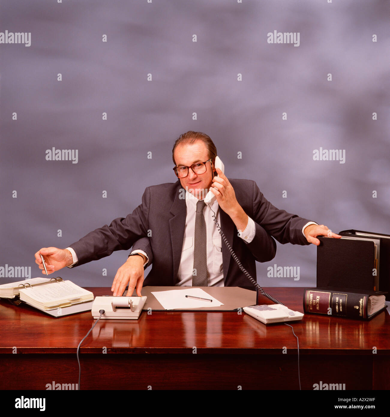 Concetto Altered digitalmente immagine di un imprenditore con quattro bracci a lavorare alla sua scrivania. Foto Stock