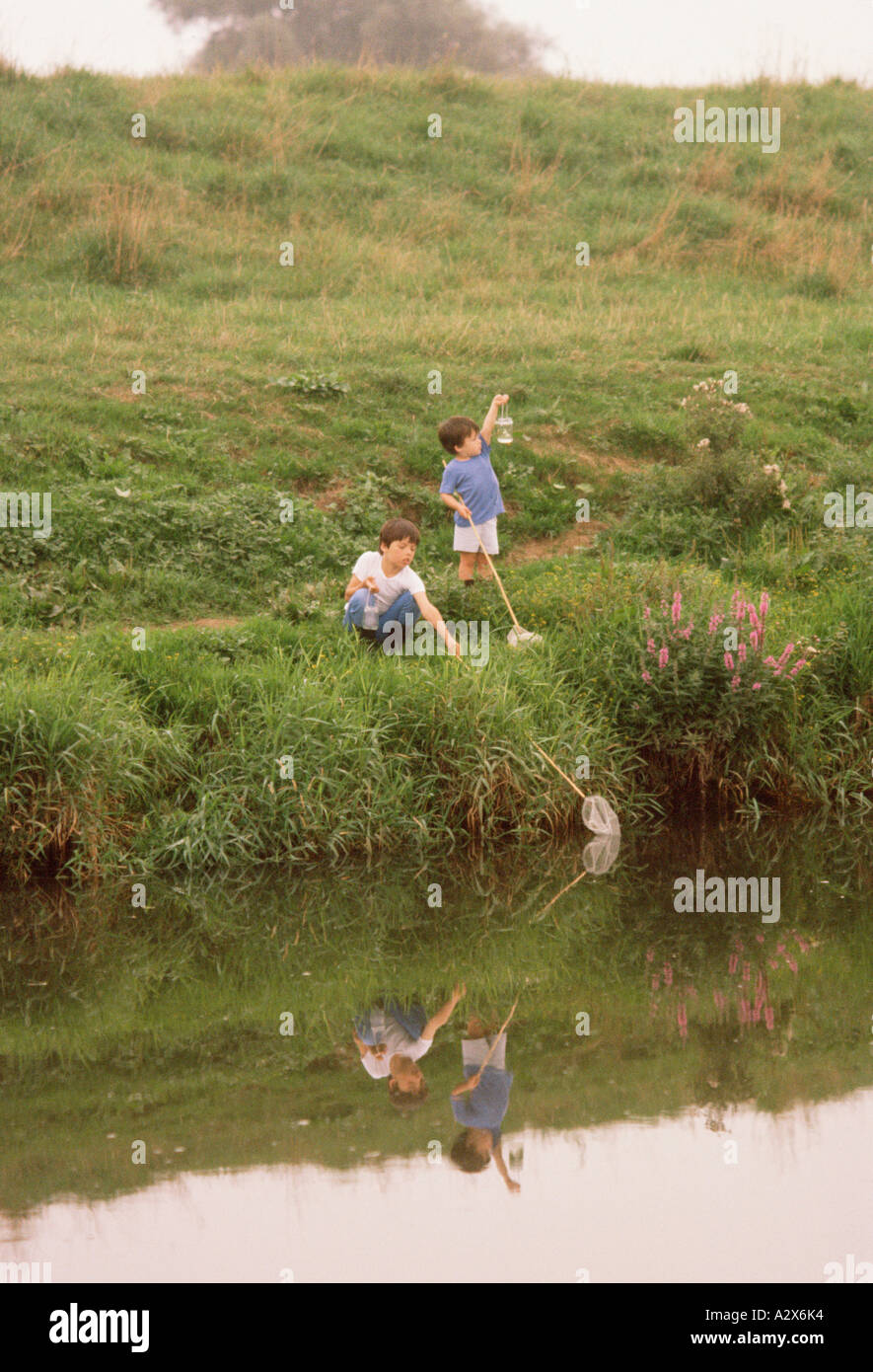 I bambini. Due ragazzi all'aperto sul lungofiume la pesca con le reti. Foto Stock