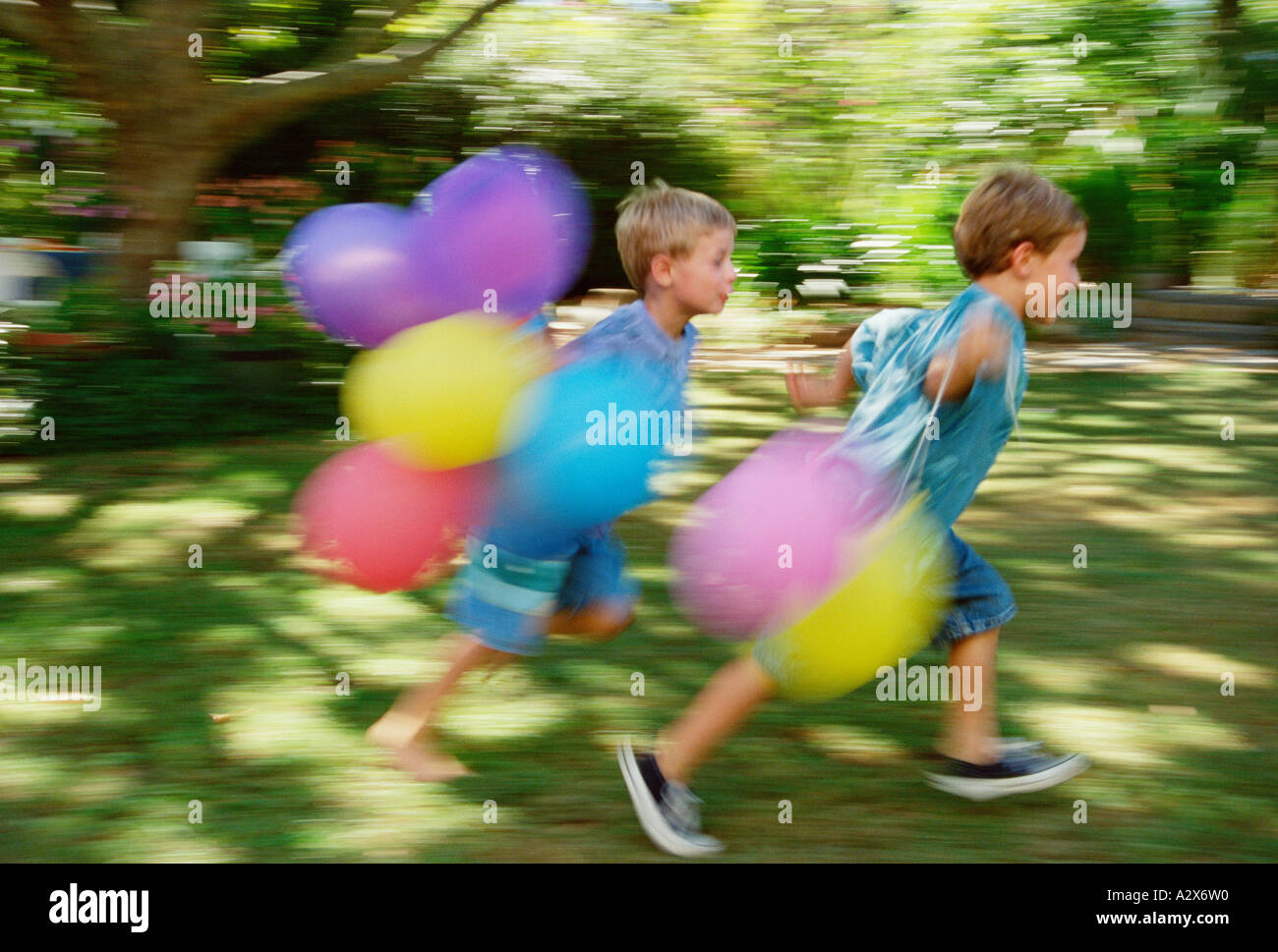 Bambini che giocano. Due ragazzi in esecuzione con palloncini in giardino. Foto Stock