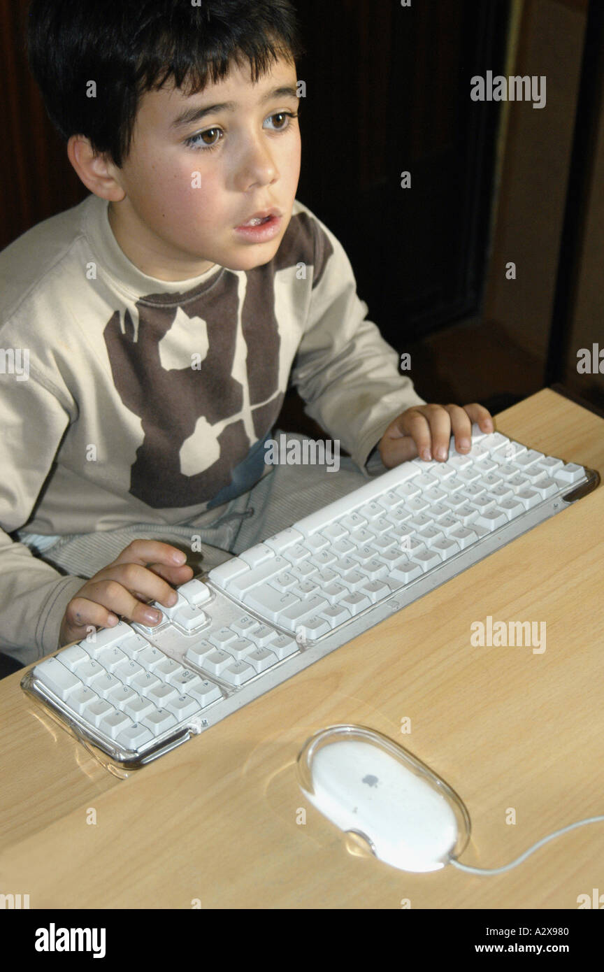 Modello rilasciato il ritratto di sette anni di vecchio ragazzo giocando con il desktop di un computer di casa Foto Stock