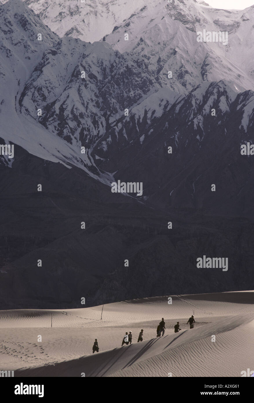 I ragazzi di ritorno da scuola attraverso le dune di sabbia in Skardu, la parte superiore della valle di Indus, Kashmir Pakistan, 1990. Foto Stock