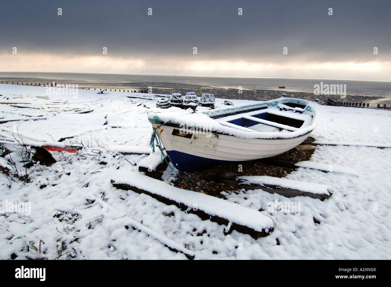 Neve su una solitaria barca da pesca a Worthing beach dopo le tempeste invernali nel Sussex e Kent in Inghilterra del Sud Foto Stock